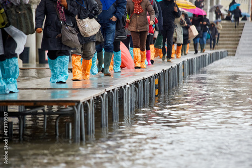 Water floods Venice footpaths, feet on raised walkway photo