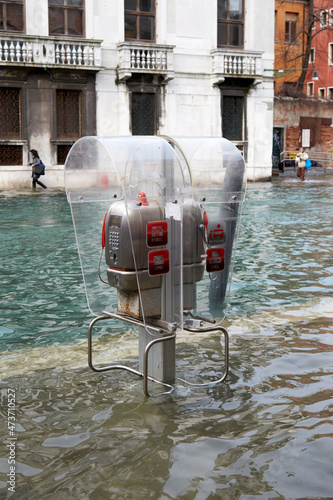 Public call phone telephone box at High tide flood in Venice