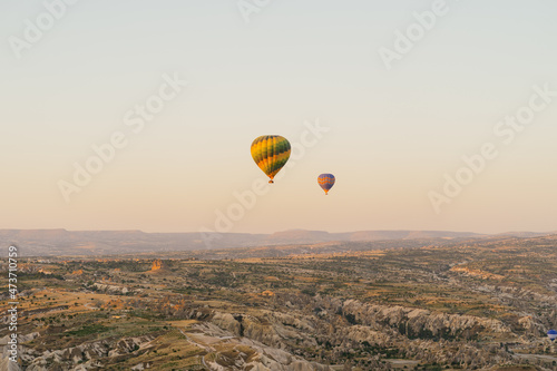 Cappadocia, Turkey - 21 July 2021: Colorful hot air balloon flying over white mountains. Hot air balloons flying in sunrise sky. Goreme mountains scenic view © diignat