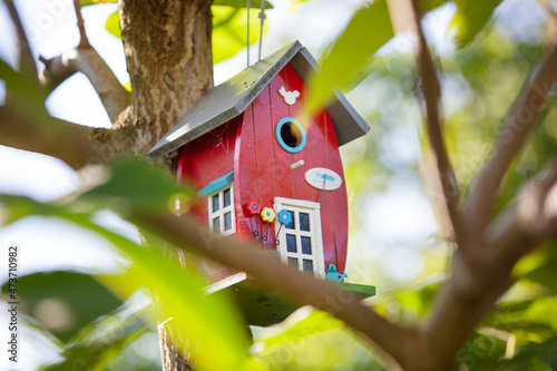 Wunderschönes, verwunschendes Vogelhäuschen hängt in einem grünen Baum.