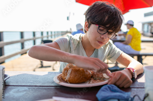 Boy eating clam chowder on bread at the port
 photo