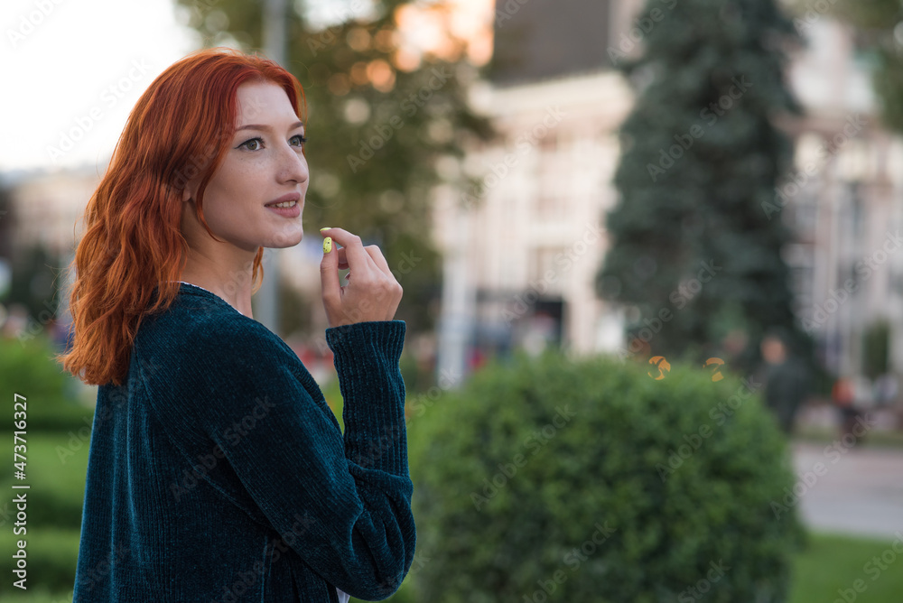 Portrait of a young, beautiful and attractive redhead Caucasian girl with freckles. Girl posing walking through the city.