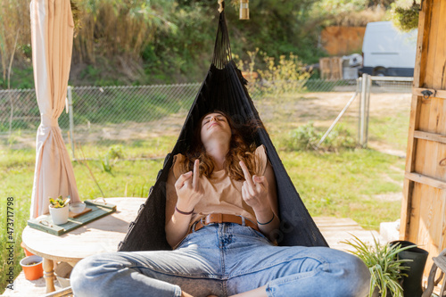 Young relaxing in hammock and flipping finger