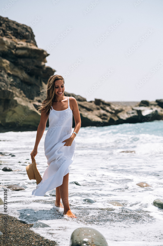 Stylish woman in dress walking along seashore Stylish woman in dress walking along seashore