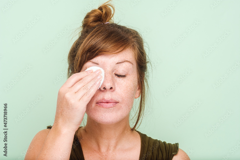 Woman With Freckles Removing Makeup From Her Eyes Woman With Freckles Removing Makeup From Her Eyes
