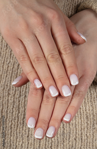 Classic white manicure on natural wool background.