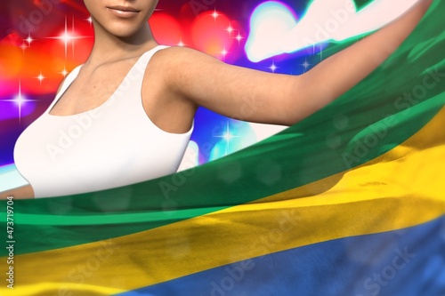 Slika na platnu young lady holds Gabon flag in front on the party lights - flag concept 3d illus