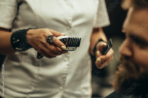 Professional barber holding a hair trimmer in her hands © Zamrznuti tonovi