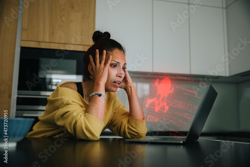 Woman with head in hands looking at danger icon laptop