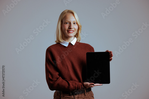 Joyful young woman, holding a tablet on the palm of her hand indoors. photo