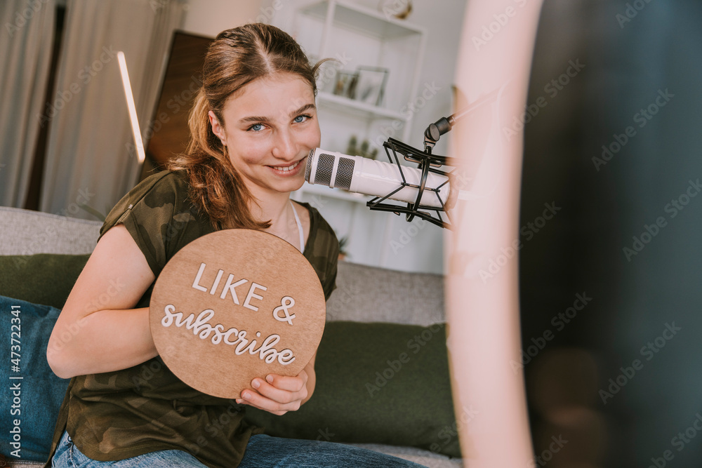 Smiling girl showing like and subscribe sign at home Stock Photo ...