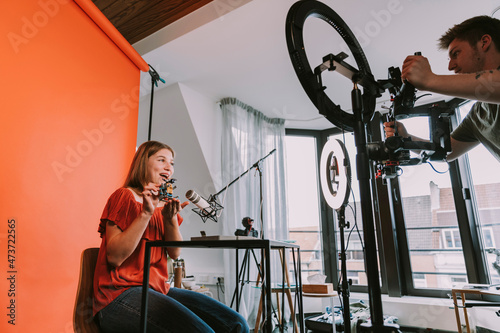 Male camera operator recording while female influencer explaining robotics at home photo