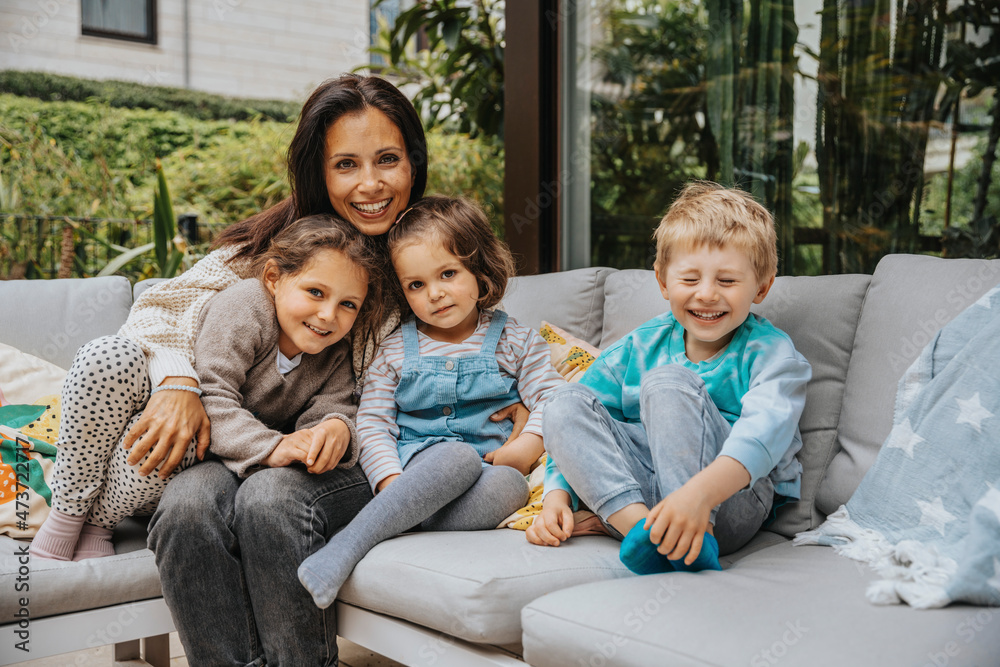 Smiling mother with children on sofa at backyard Smiling mother with children on sofa at backyard