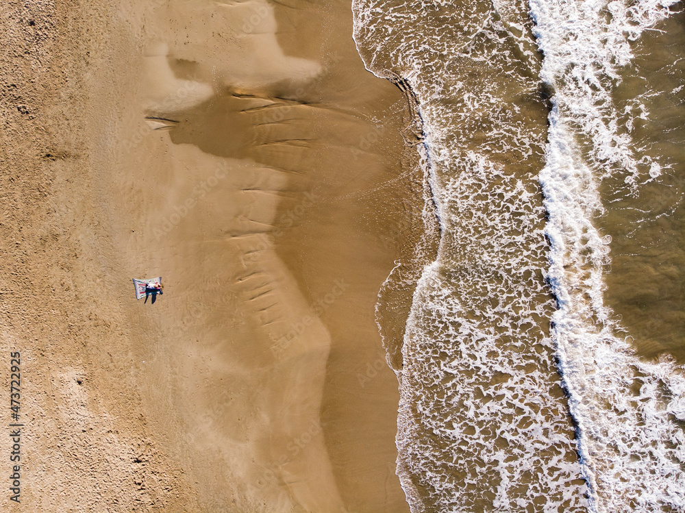 Spain, Sitges, aerial view of mother and daughter lying on sandy beach