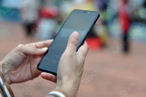 Close-up of a young woman's hand using a mobile phone in a city park