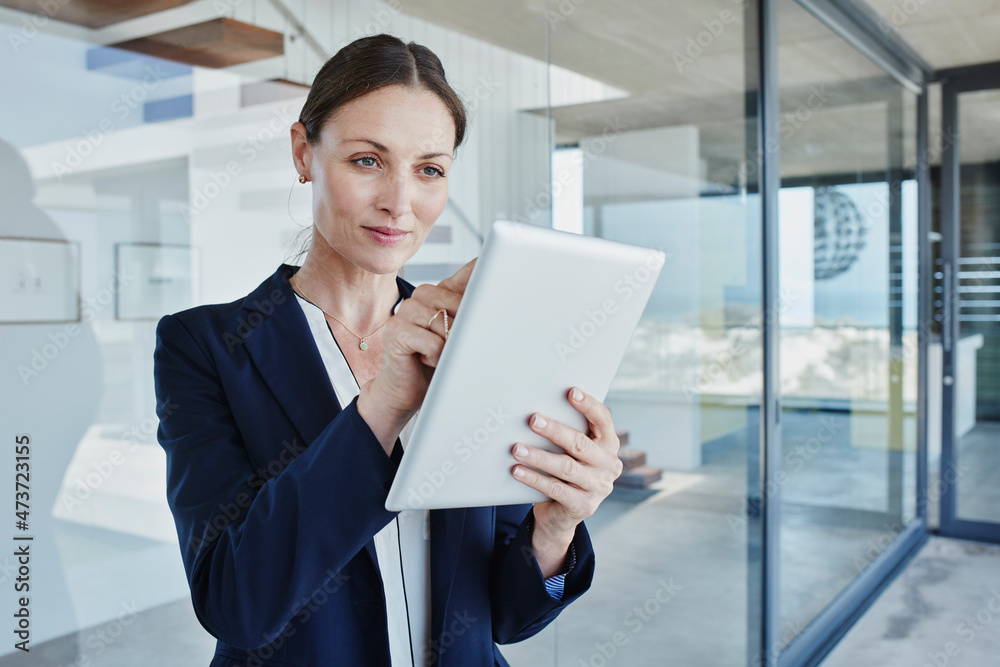 Businesswoman using digital tablet while standing by glass wall Businesswoman using digital tablet while standing by glass wall