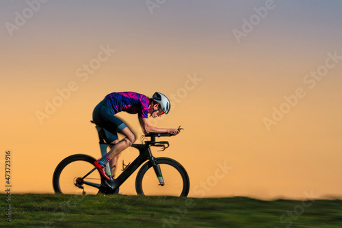 Male sportsperson triathlon riding bicycle on land during sunset photo