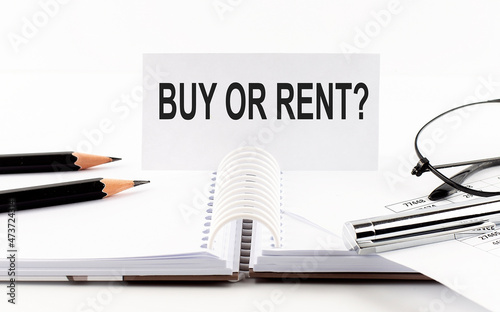 Text BUY OR RENT on paper card,pen, pencils, glasses,financial documentation on table - business concept