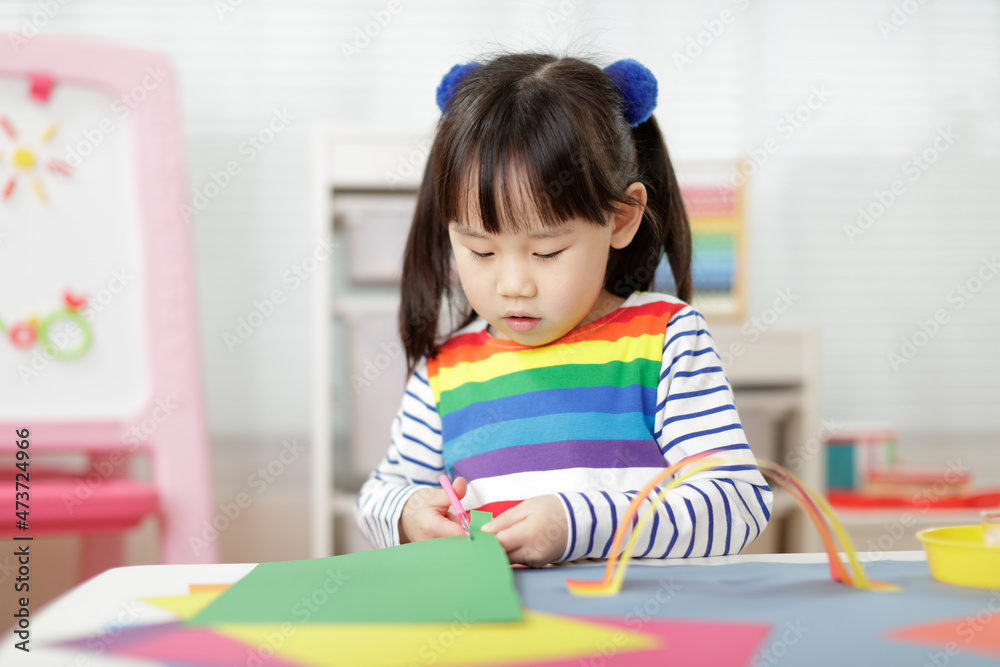 young girl making paper rainbow craft for homeschooling