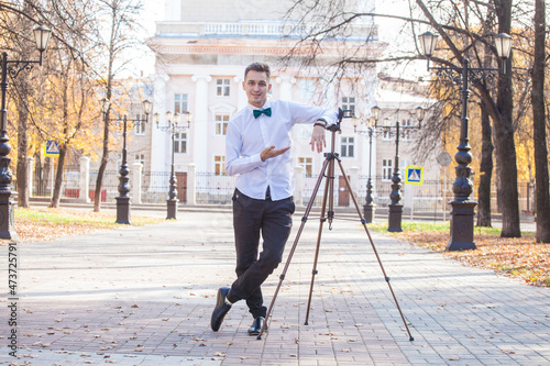 Young guy blogger on a walk in the fall with a tripod and a phone