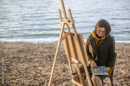 the artist paints on the shore of the lake