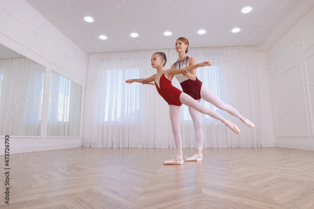 Little ballerina and her teacher practicing dance moves in studio. Space for text Little ballerina and her teacher practicing dance moves in studio. Space for text