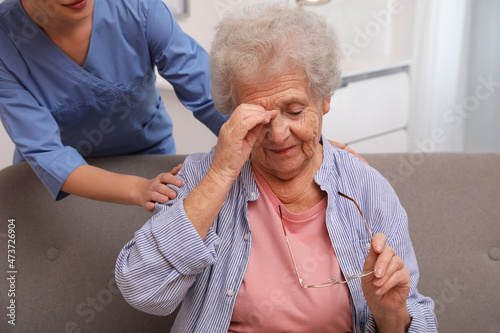 Nurse taking care of senior woman with headache indoors photo