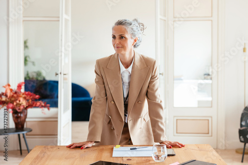 Mature female boss leaning on table photo