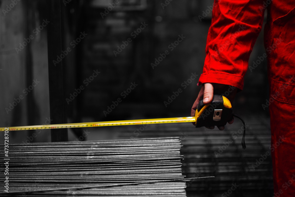 Closeup hand of a worker holding a steel tape measure tool in workshop of a plant or factory