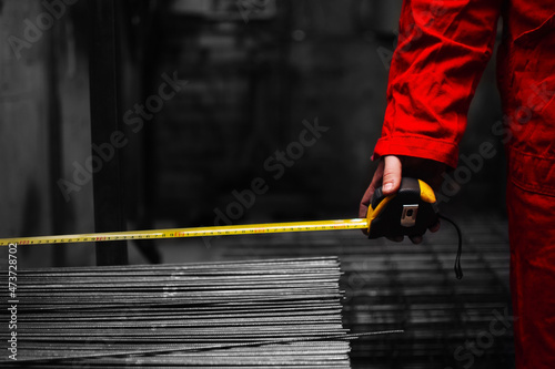 Closeup hand of a worker holding a steel tape measure tool in workshop of a plant or factory