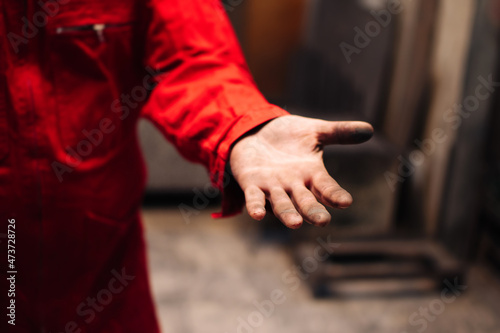 Closeup palm of a worker in workshop of factory or production facility (selective focus on fingers)