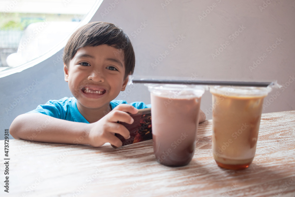 smiling handsome boy sitting and playing smartphone smiling handsome boy sitting and playing smartphone