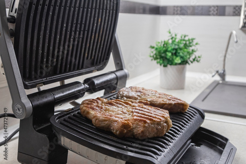 Hot steak on the electric grill at home in the kitchen