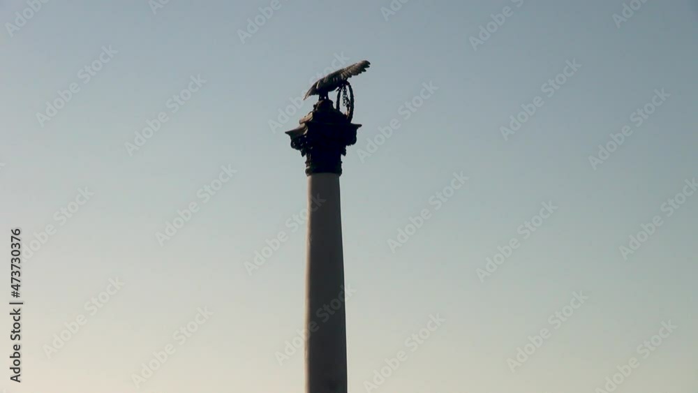 Monument to sunken ships at sunset. Pedestal with bronze eagle on background of passing ferry. Quiet and measured life in Crimea after 2014 referendum. Sevastopol, Crimea, October 8, 2014. Monument to sunken ships at sunset. Pedestal with bronze eagle on background of passing ferry. Quiet and measured life in Crimea after 2014 referendum. Sevastopol, Crimea, October 8, 2014.