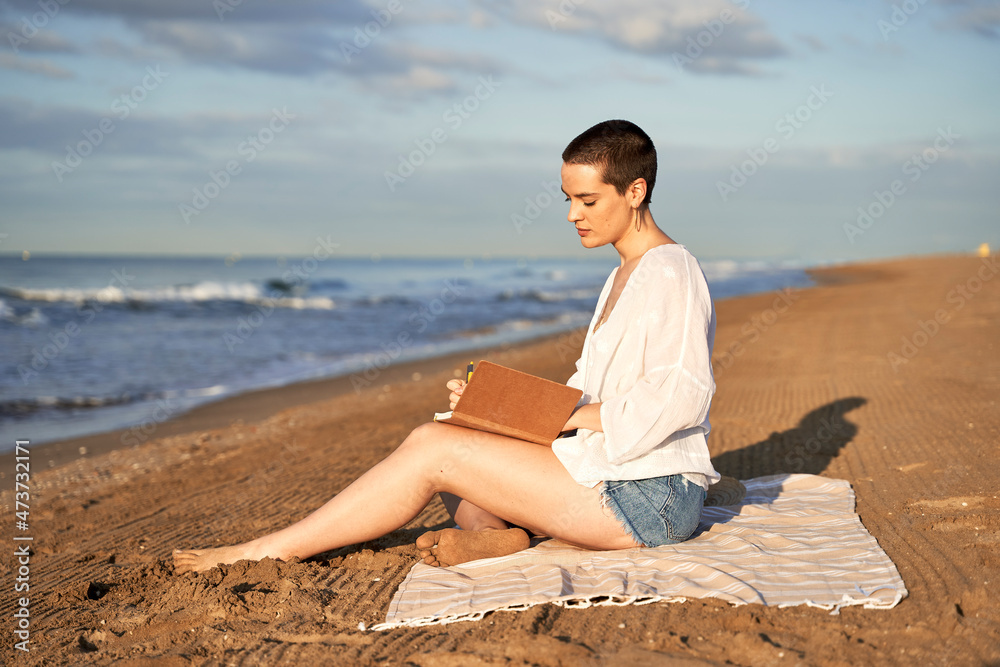 Woman writing in diary while sitting on blanket Woman writing in diary while sitting on blanket