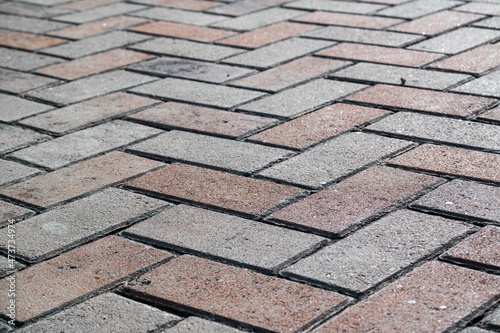 Mosaic paving of red and gray bricks diagonal on the ground.