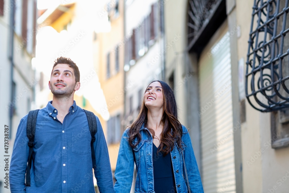 Smiling couple looking away while standing at city street Smiling couple looking away while standing at city street