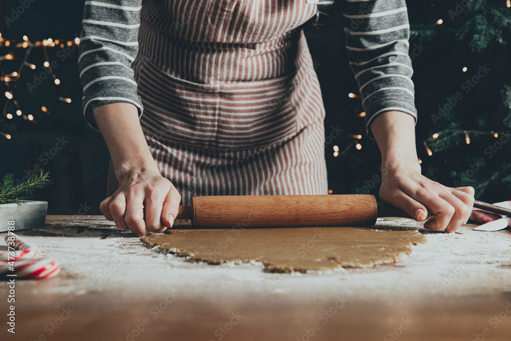 Merry Christmas, Happy New Year. Gingerbread cooking, cake or strudel baking. A young woman or mother rolls out the dough with a rocking chair for extruding and cutting out cookies. High quality photo Merry Christmas, Happy New Year. Gingerbread cooking, cake or strudel baking. A young woman or mother rolls out the dough with a rocking chair for extruding and cutting out cookies. High quality photo