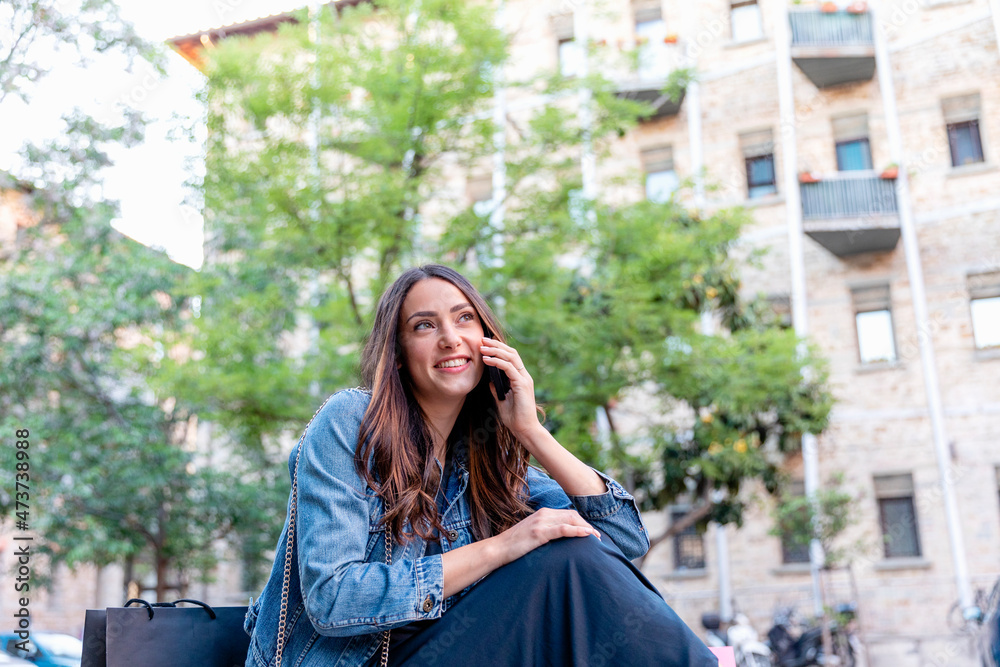 Smiling woman looking away while talking on smart phone in city Smiling woman looking away while talking on smart phone in city