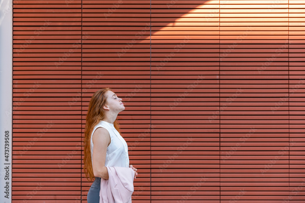 Young businesswoman with eyes closed standing by metal wall Young businesswoman with eyes closed standing by metal wall
