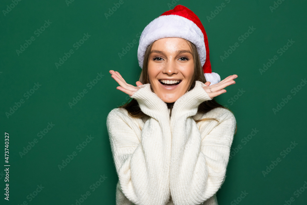 Young woman wearing Christmas Santa hat over isolated green background smiling with her hands on her chest and grateful gesture on her face. Young woman wearing Christmas Santa hat over isolated green background smiling with her hands on her chest and grateful gesture on her face.