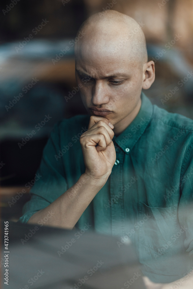 Male cafe owner with hand on chin using digital tablet Male cafe owner with hand on chin using digital tablet