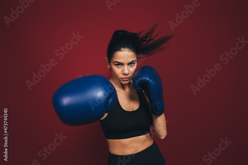 Female athlete practicing boxing in front of maroon background photo