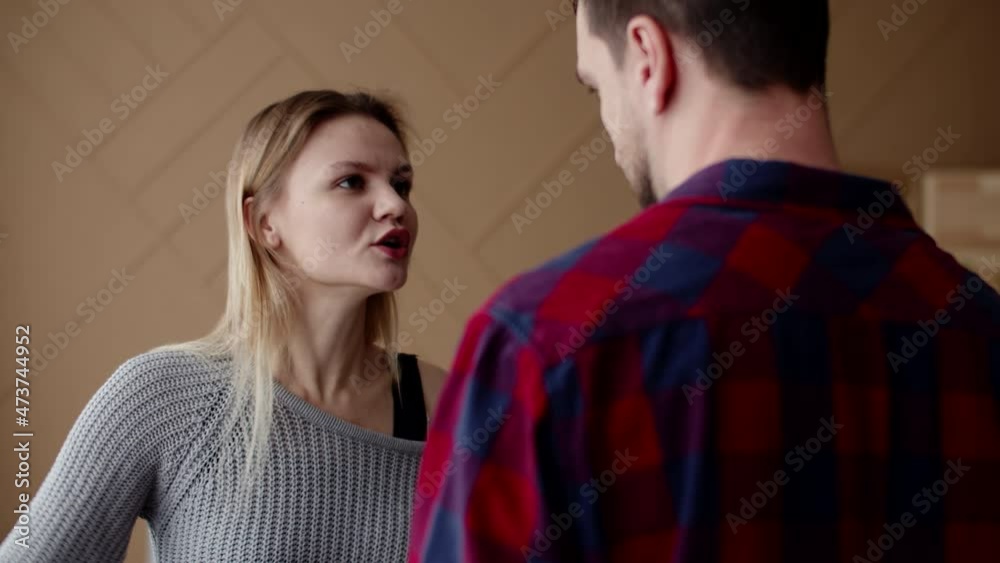 Wife emotionally swearing at husband, gesturing with hands, standing in front of him, front view. Wife accuses husband and quarrels with him. Concept of family conflict Wife emotionally swearing at husband, gesturing with hands, standing in front of him, front view. Wife accuses husband and quarrels with him. Concept of family conflict