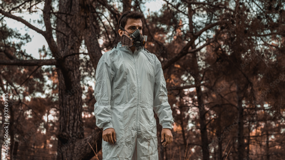 Man in white overalls wearing a gas mask in a post apocalyptic nature Man in white overalls wearing a gas mask in a post apocalyptic nature