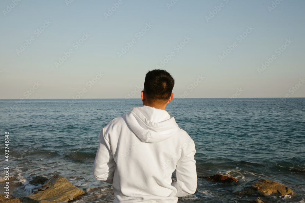 Back view of young man , posing outdoor close to ocean.