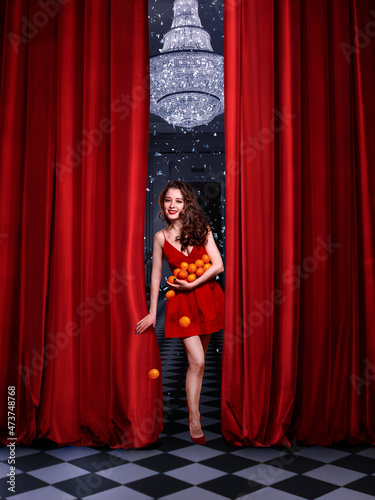 Beautiful woman with a tangerines behind a curtain in anticipation of Christmas.