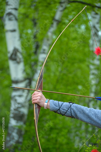 professional archers shooting with modern longbows at meadow