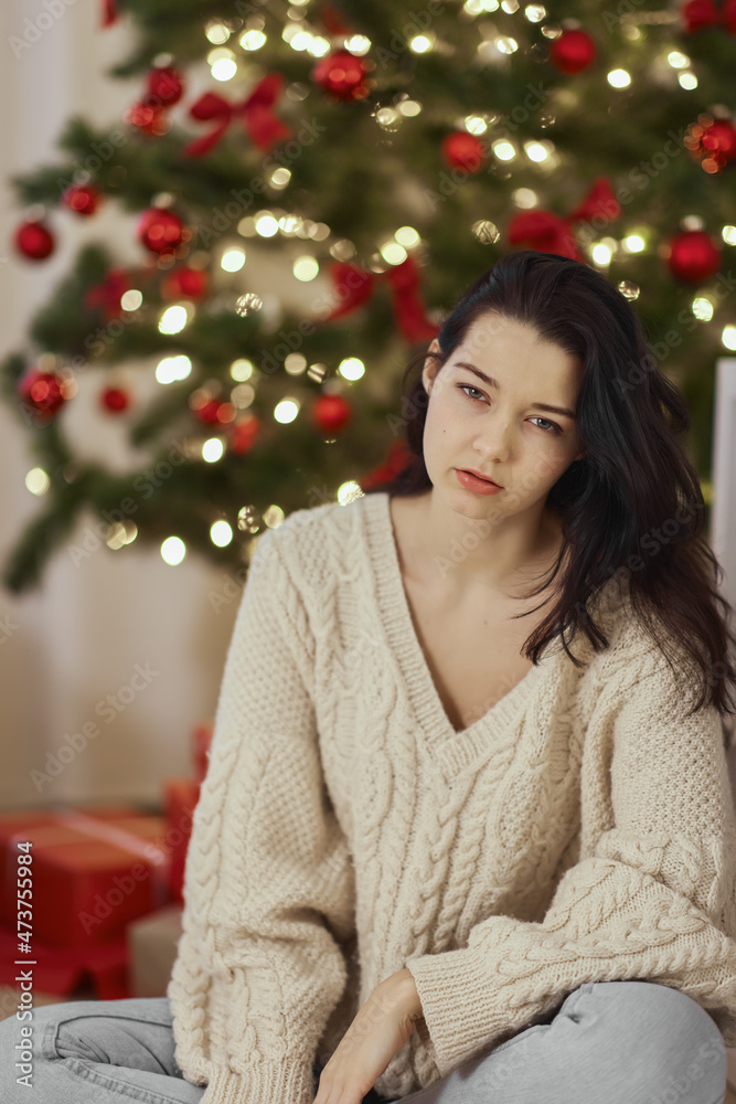 Bad Christmas, feeling sick after Christmas party. Disappointed and sleepy woman. Woman with hangover sitting at home against the Christmas tree. Bad Christmas, feeling sick after Christmas party. Disappointed and sleepy woman. Woman with hangover sitting at home against the Christmas tree.