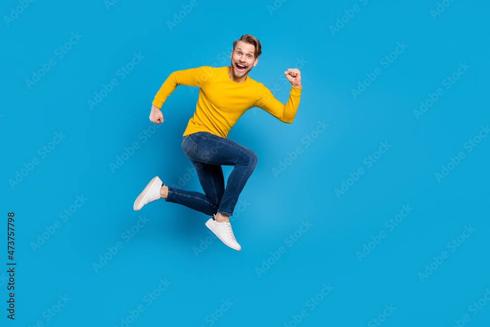Full length side profile body size photo of young man jumping high running fast isolated vivid blue color background